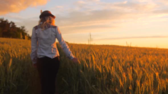 Bohemian woman walking through barley field during sunset