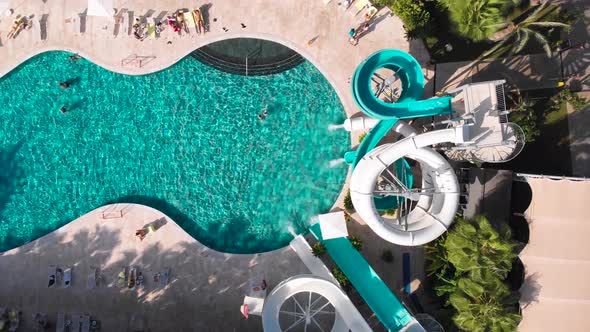 Fly Over a Large Pool with Blue Water and a Lot of Tourists in Hot Weather alt