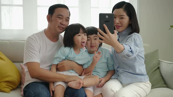 Asian family relaxing on the sofa in the living room, having fun selfies, family relationship