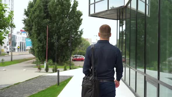 Businessman in a Dark Blue Shirt Walking Down the Street. View From the Back alt