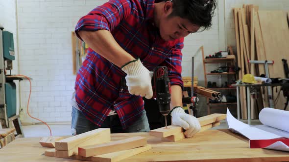 Carpenter use a hand drill to drill the wood on the workshop table in the workshop