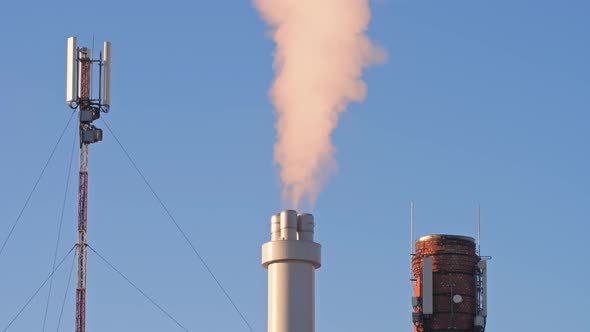 The chimney from the factory emits dirty smoke, there is an old red brick
