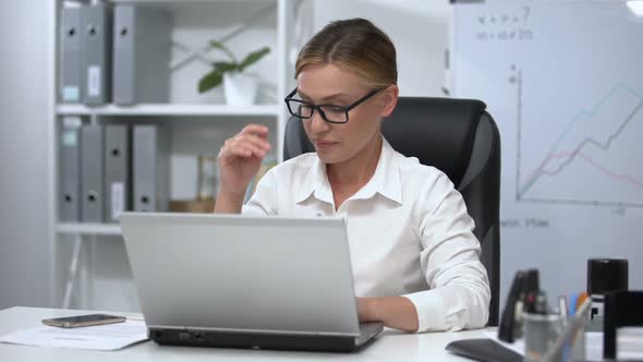 Exhausted Woman Putting Off Glasses and Rubbing Her Tired Eyes, Laptop Work