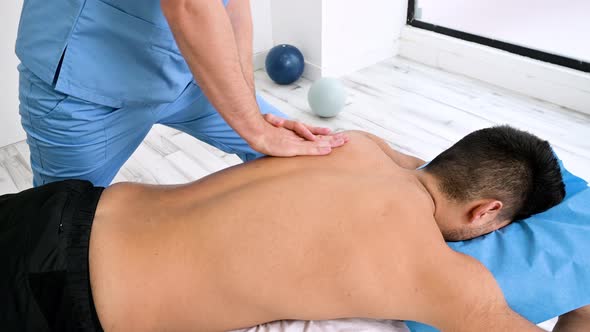 Physiotherapist Massaging the Back of a Young Athlete in the Sports Rehabilitation Clinic alt
