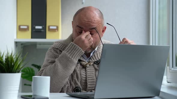 Tired Middle Aged Man in Eyewear Working with Computer Remotely Sitting at Home or in Office alt