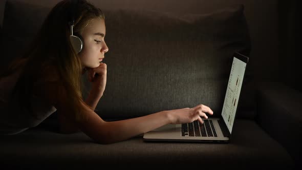 Girl with Headphones and Her Computer Relaxing on Some Bed alt