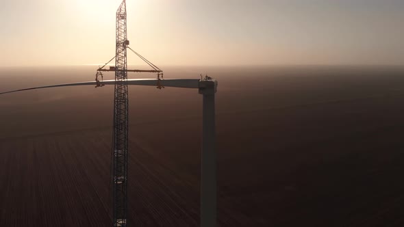 Silhouette of Tower Crane Installing Blade to Wind Turbine