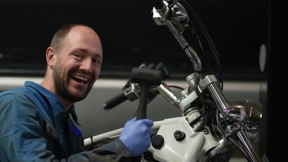 guy mechanic in blue overalls next to a motorcycle