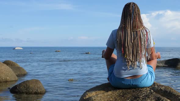 Unrecognizable Woman Sits in Lotus Position on Calm Sea Water Surface Background