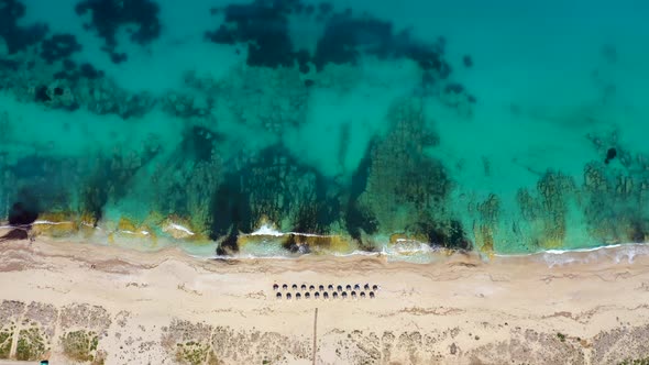 Umbrellas lined up on the sandy beach by the turquoise sea. alt