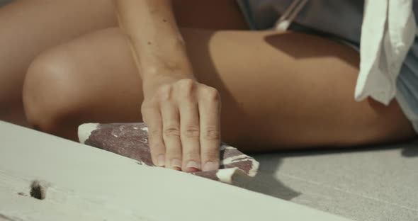 Close Up of Young Woman Hands Sanding the Wooden Doorsteps at Sunny Morning alt