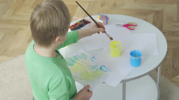 View From Behind a Boy with Down Syndrome Drawing at Home