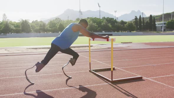 Disabled mixed race man with prosthetic legs stretching with a hurdle alt
