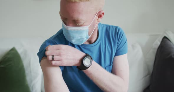 Happy albino african american man wearing face mask, with a plaster after vaccination alt