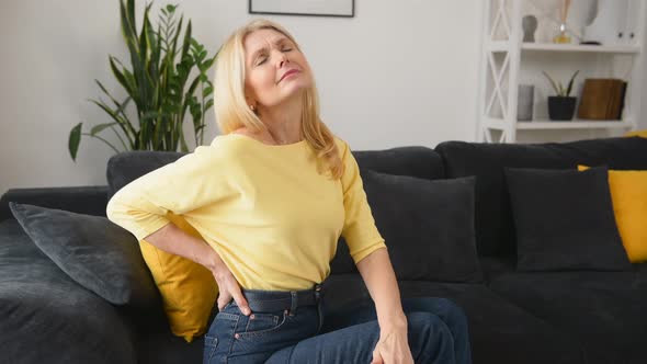 Blondehaired Woman Felt a Sharp Pain in Loin Sitting on the Sofa at Home
