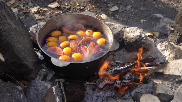 Cauldron with a stewed fruit is heated on the bonfire at the campsite alt