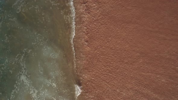 Aerial view of sandy portuguese beach with rolling waves; sunny day, top down view