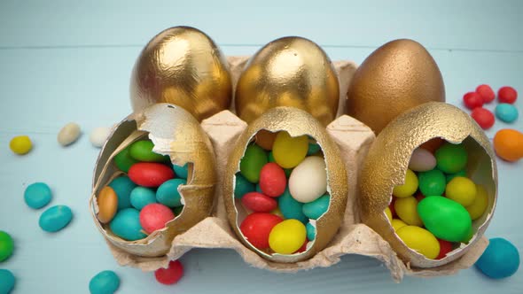 Golden Decorative Easter Eggs Filled with Colorful Candies on Wooden Table Close Up