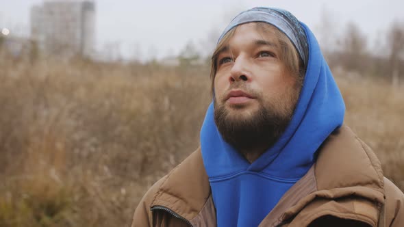 A Lonely Longhaired Bearded Man in an Autumn Park Raises His Eyes to the Sky Silently Suffering From alt
