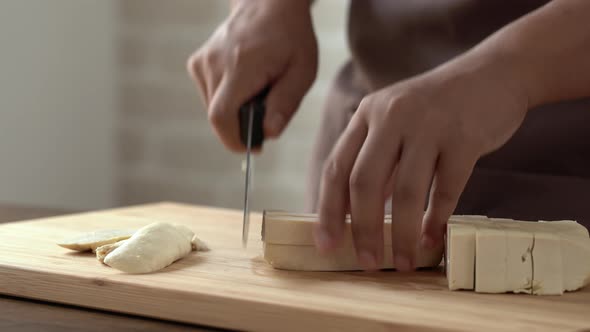 Closeup of chef hands slicing and dicing tofu with knife