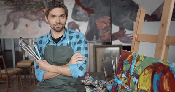 Male Artist Holding Brushes in Studio Portrait