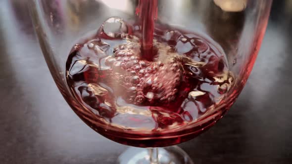 red wine is poured into a glass in the kitchen