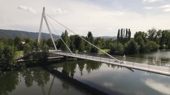 One person walking on pedestrian bridge over river Tamega, Chaves in Portugal. Aerial circling alt