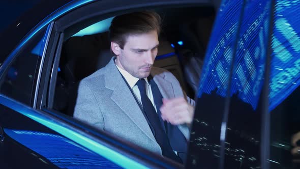 Slow Motion Young Businessman Sitting in a Moving Car and Using Laptop Man Top Manager in a Suit is alt
