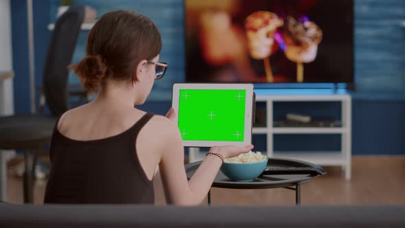 Back View of Young Woman Holding Digital Tablet with Green Screen Watching Social Media Video alt
