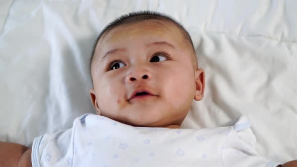 slow-motion of happy baby lying on a bed at home