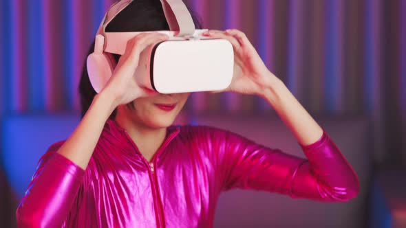 Young asian woman is using virtual reality headset. Neon light studio portrait alt