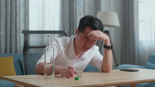 Drunk, Depressed Asian Man Pouring Vodka In A Shot Glass Before Drinking And Using A Fist Smashing alt
