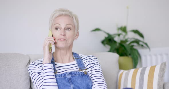 Mature woman sitting on sofa talking on the phone