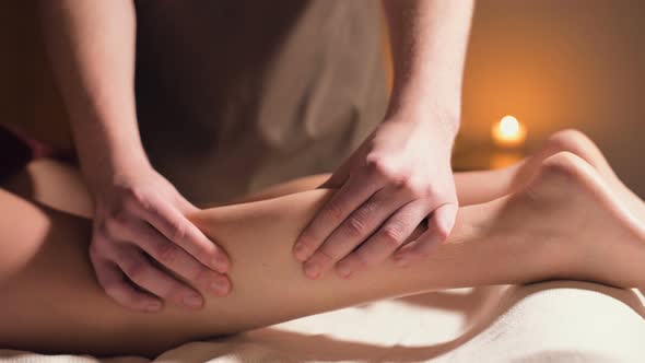 Close-up of the Hand Massage of the Calf Muscle. A Professional Massage Therapist Massages a Woman's alt