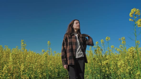 Woman walk in yellow flowering rapeseed field