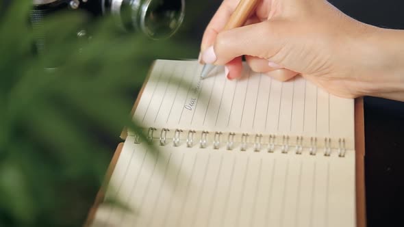 Close-up of the hands of a young unidentified woman sitting at a table