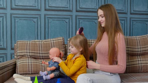 Woman Taking Care Brushing Hair of Her Sister Child Girl in Living Room Kid Playing with Toy Doll alt
