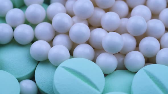 White Round Small Granules Lie Among Green Pills and Rotate Closeup alt