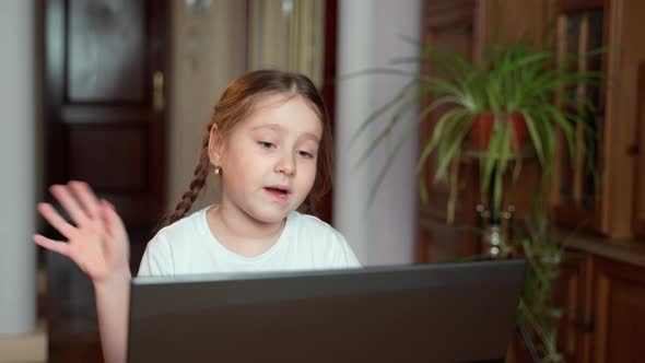 Young, beautiful little girl studying working in front of a computer at home alt