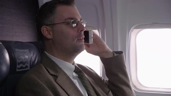 Businessman talking on cell phone on airplane flight