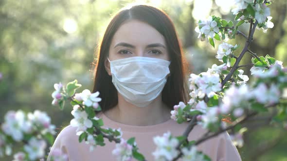 Woman in Medical Mask in Apple Blossoms in Spring alt