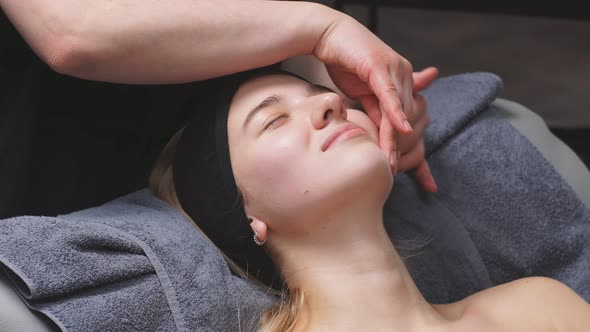 Young Woman in a Chic Beauty Salon Gets a Facial Massage and Beauty Treatments for Skin Care alt
