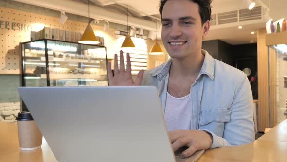 Video Chat in Cafe on Laptop By Young Man Talking with Customers alt