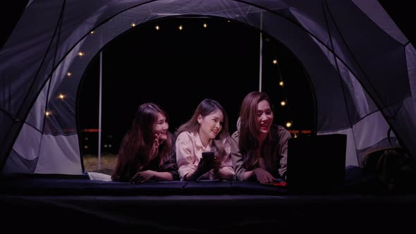 at night,Asian young women group friend are enjoy using a laptop to search the internet while campin