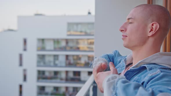 Bald Caucasian Man Stretching His Arms on Balcony and Smiling Being Positive About the Day alt