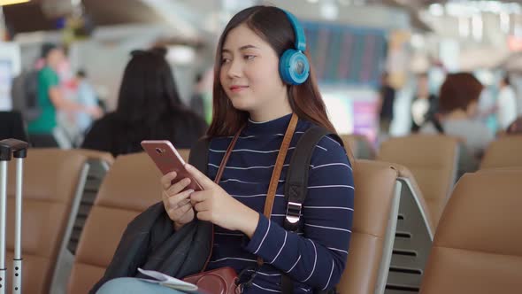 Young traveler woman use smartphone and listening music at airport