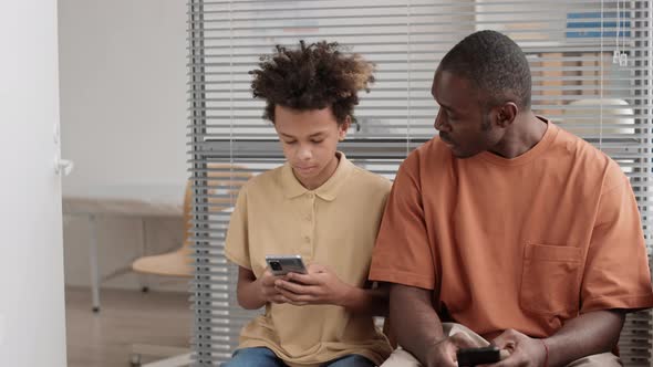 African Man and Boy Talking Indoors alt