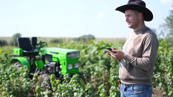 A Village Worker Speaks on the Phone Next to His Tractor alt