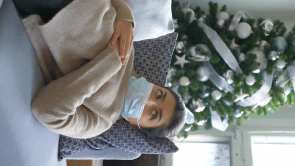 Close-Up of A Young Indian Sick Woman in a Mask Lying on A Sofa At Home in A Bright Cozy Room alt