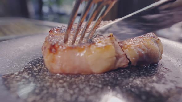 Meat Steak Is Cut with a Knife. Piece of Meat Is Lifting Up with fork.Tasty Food.